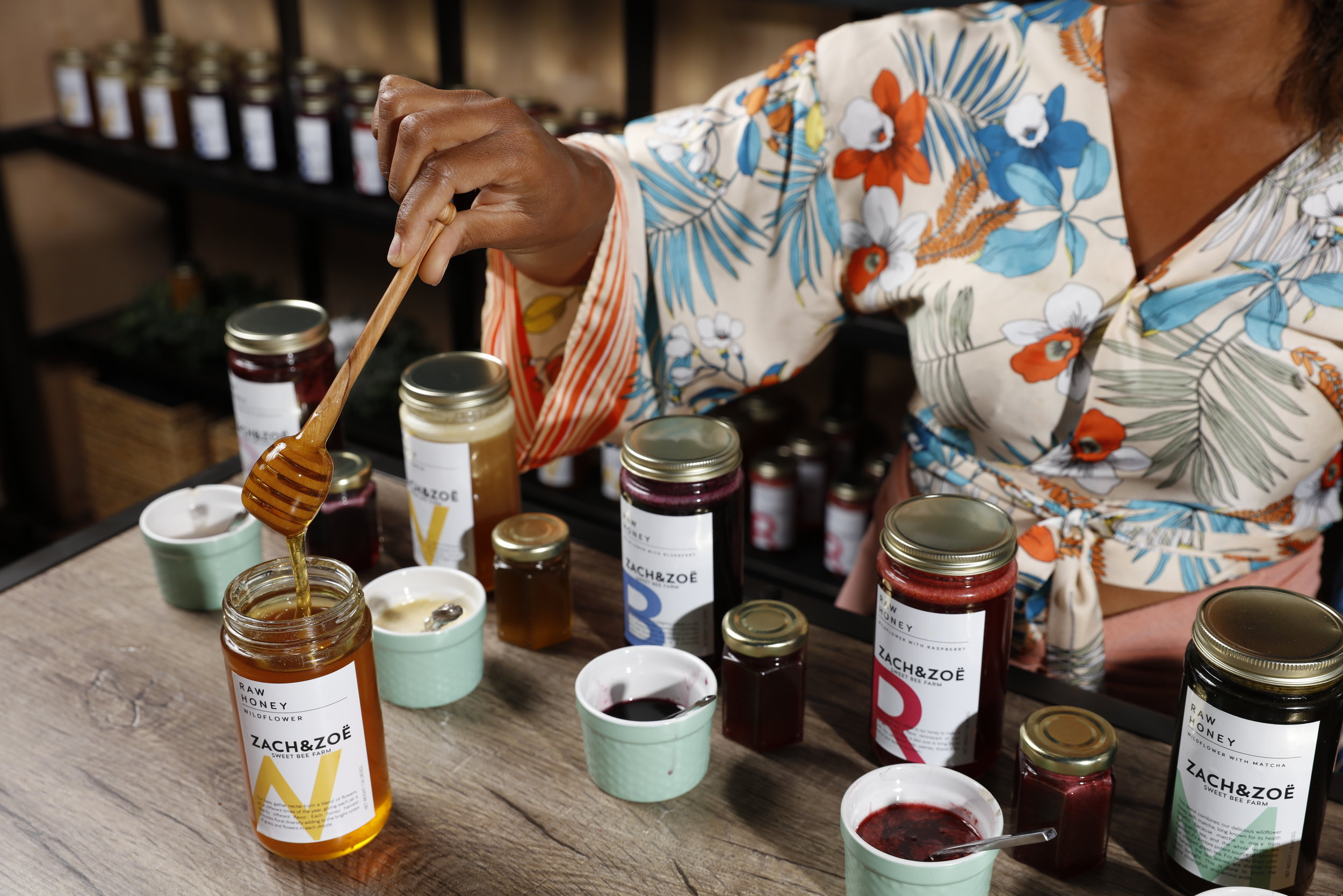 woman holding a wooden honey dipper dipping into honey  dipping 