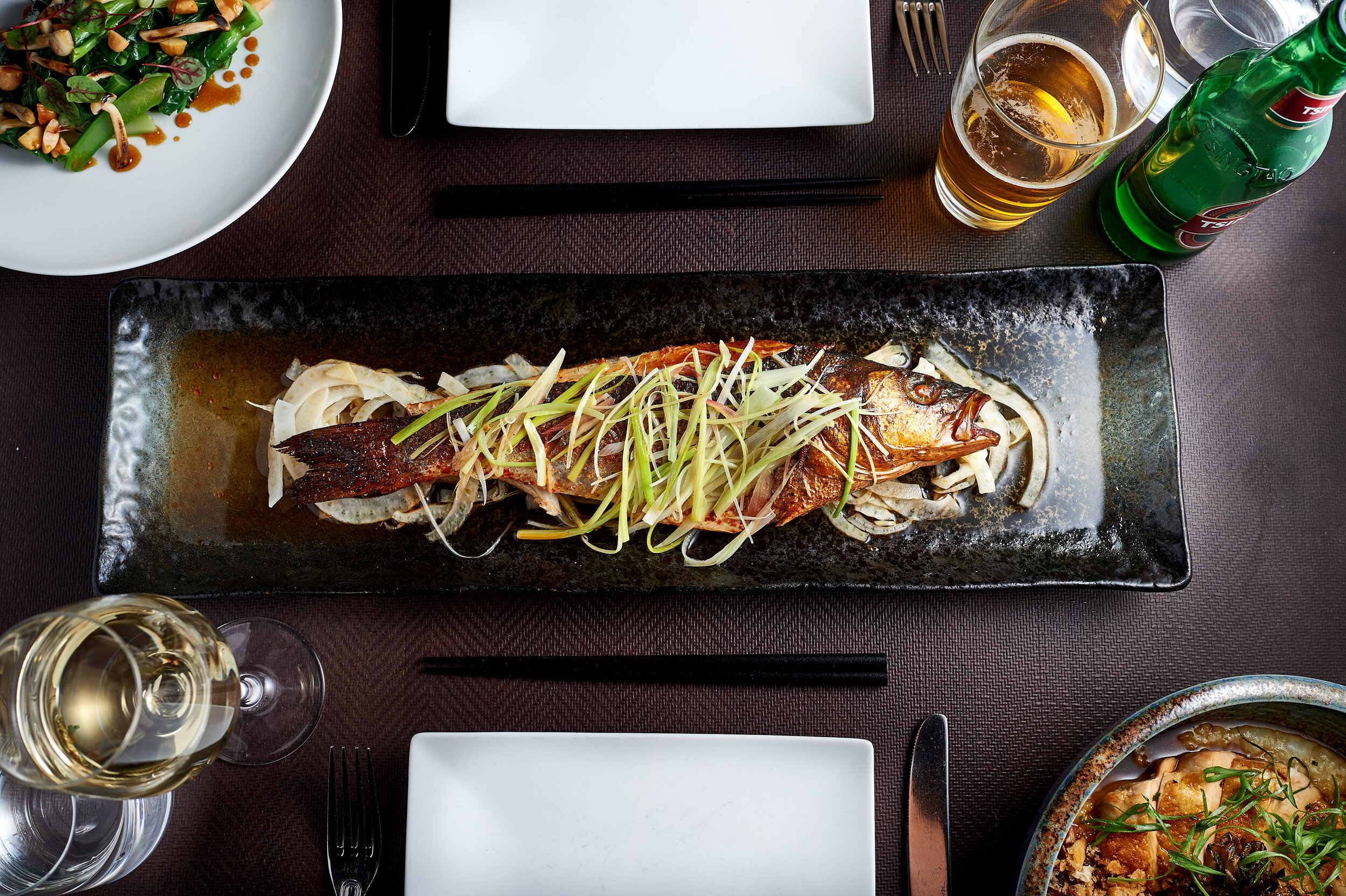 overhead shot of whole roasted fish with cut veggies on top