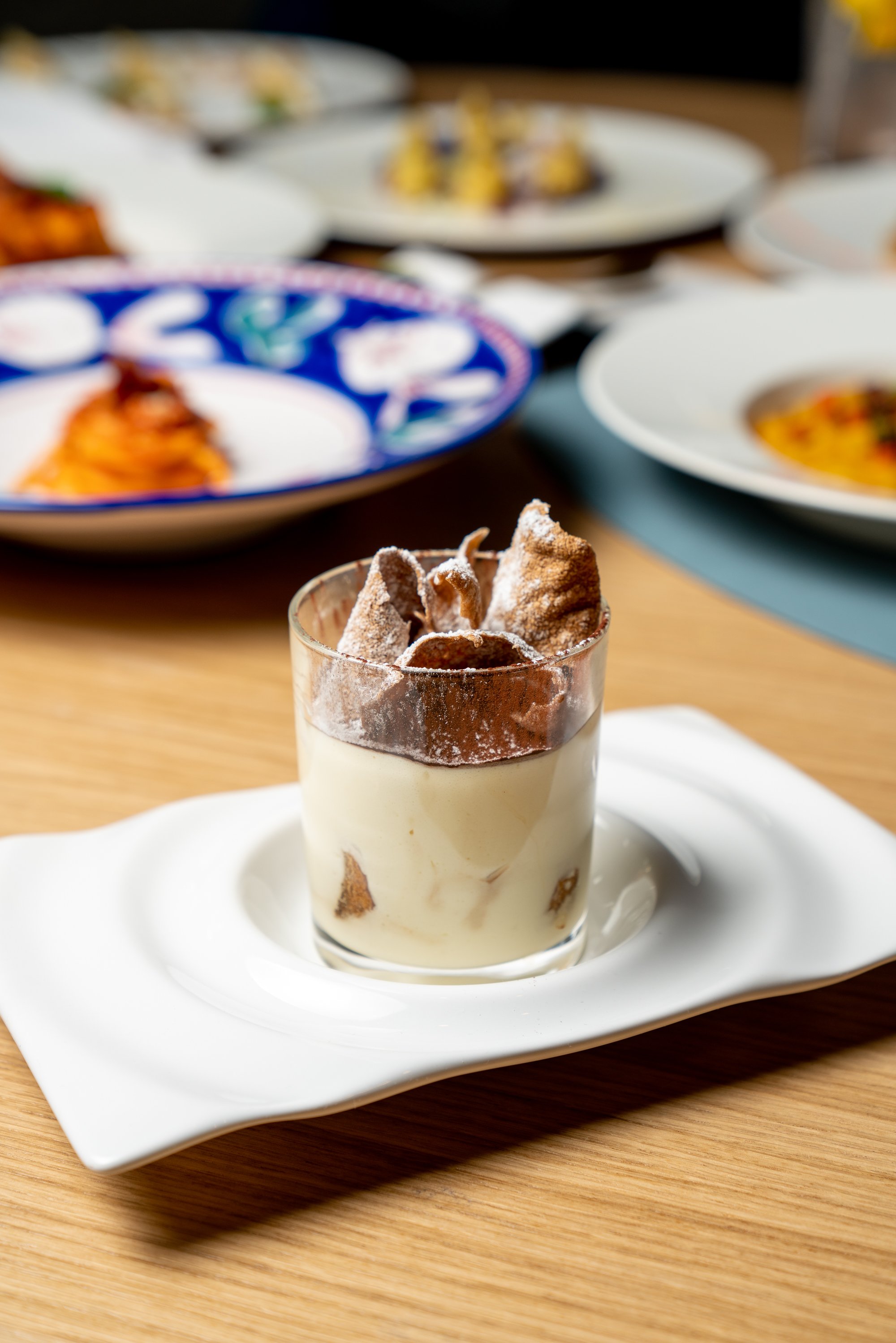 tiramisu in glass topped with crispy pasta shells and powdered sugar