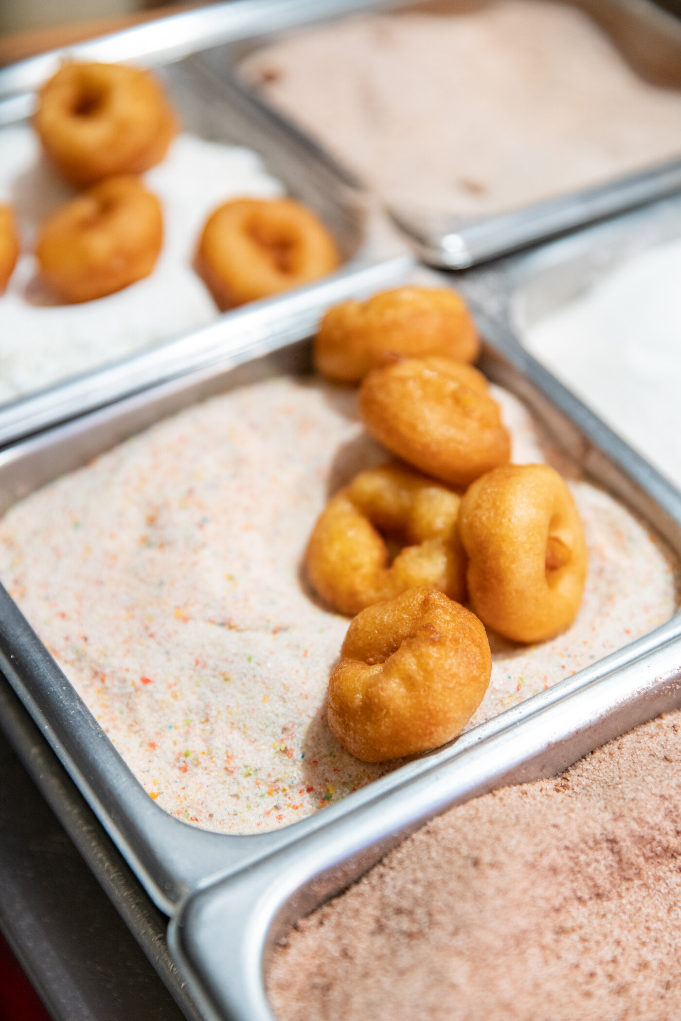 plain doughnuts lying in a bowl of sugar