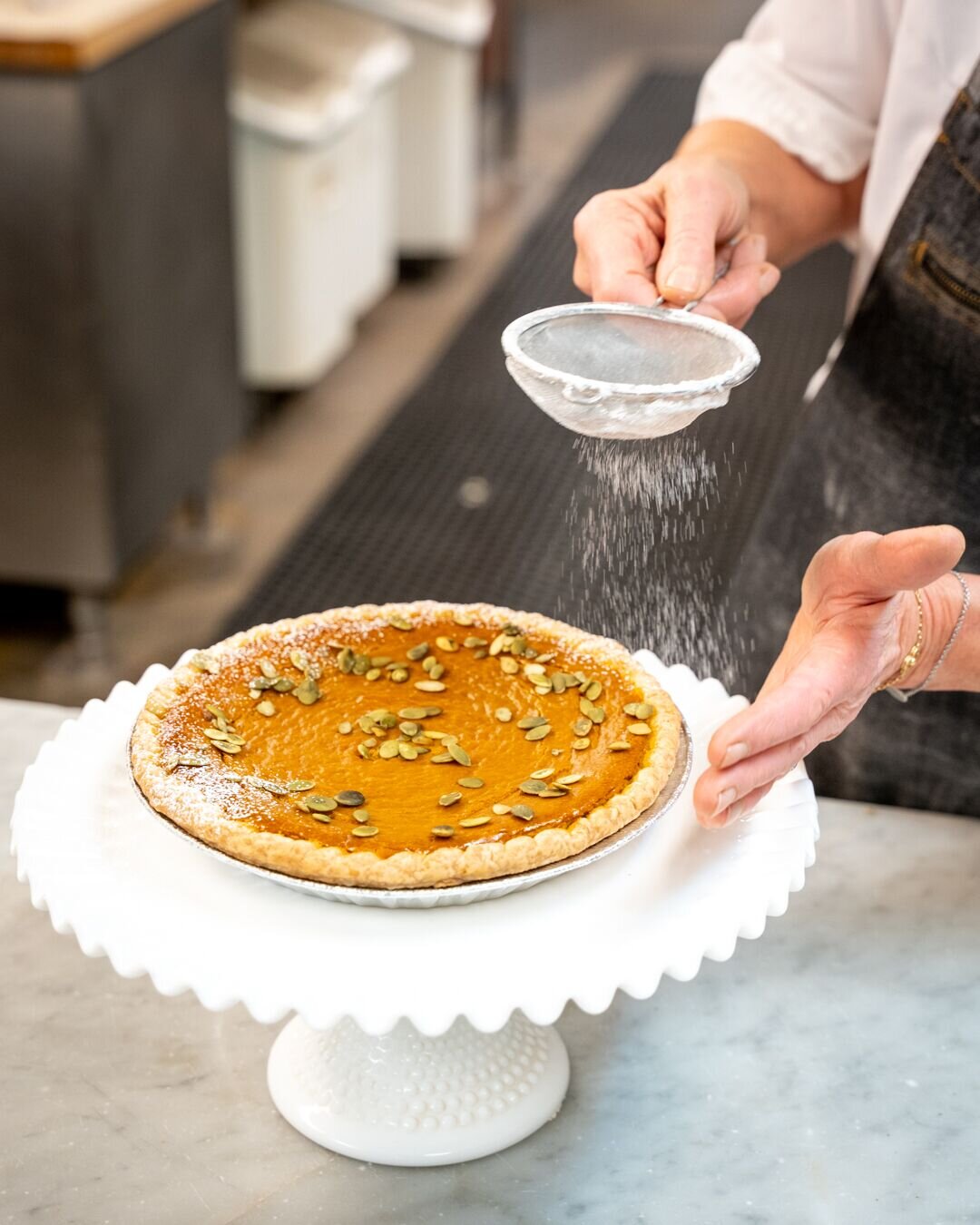 pumpkin pie being sprinkled with powdered sugar 