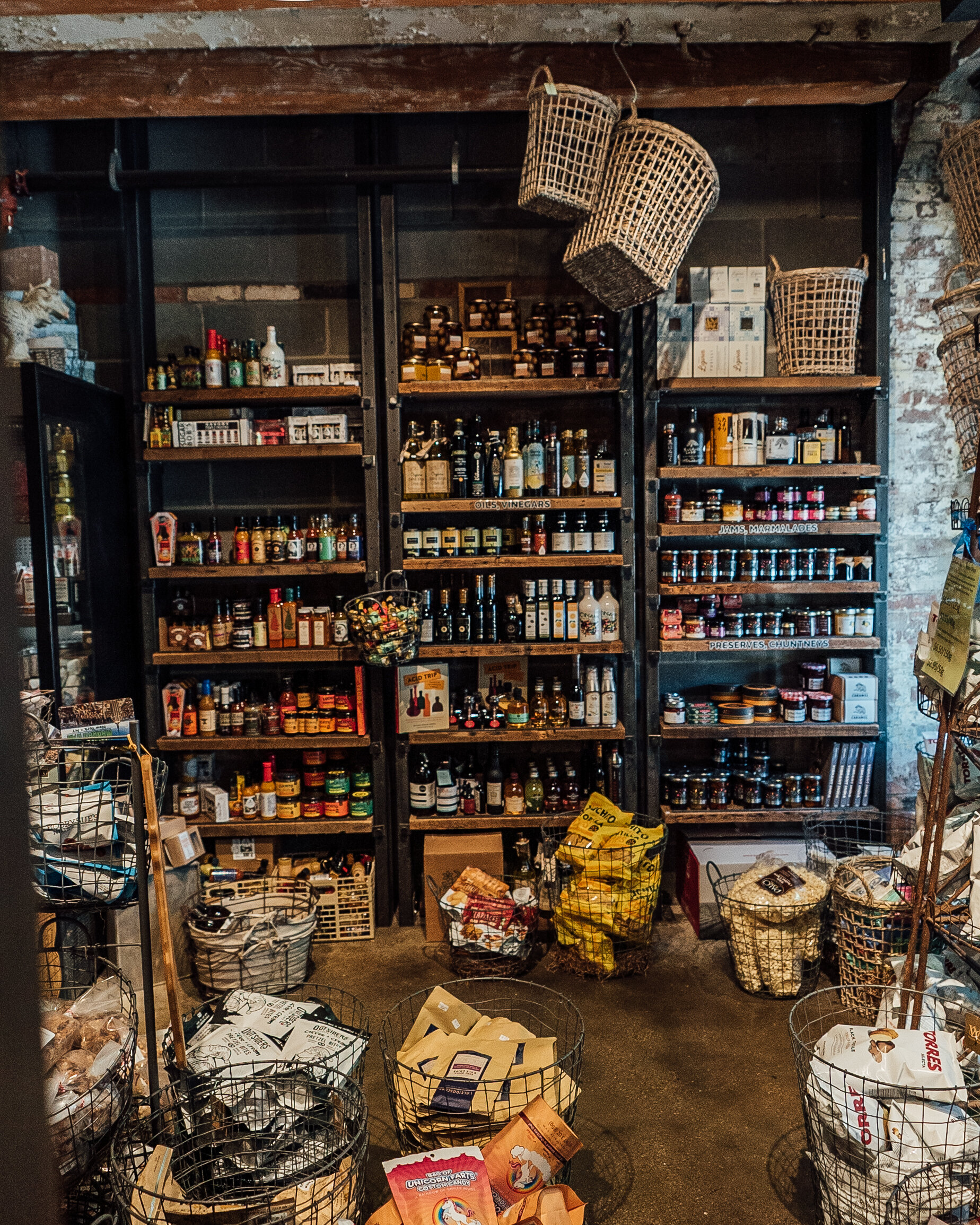 shelves holding sauces with baskets on the ground holding chips and other packaged foods