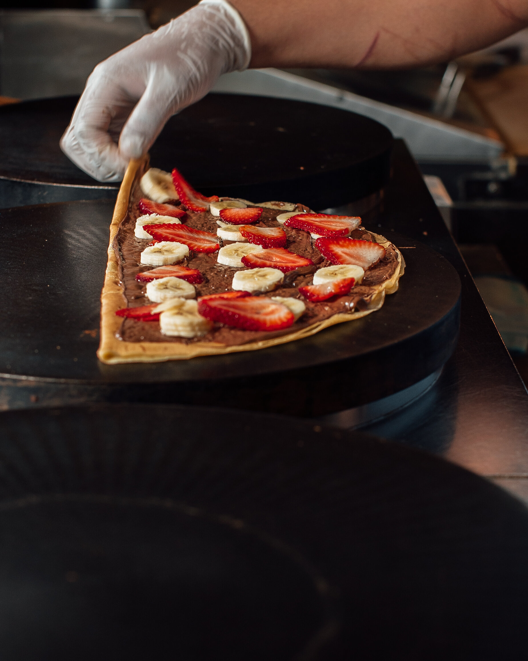 crepe with nutella strawberries and bananas on a griddle about to be folded