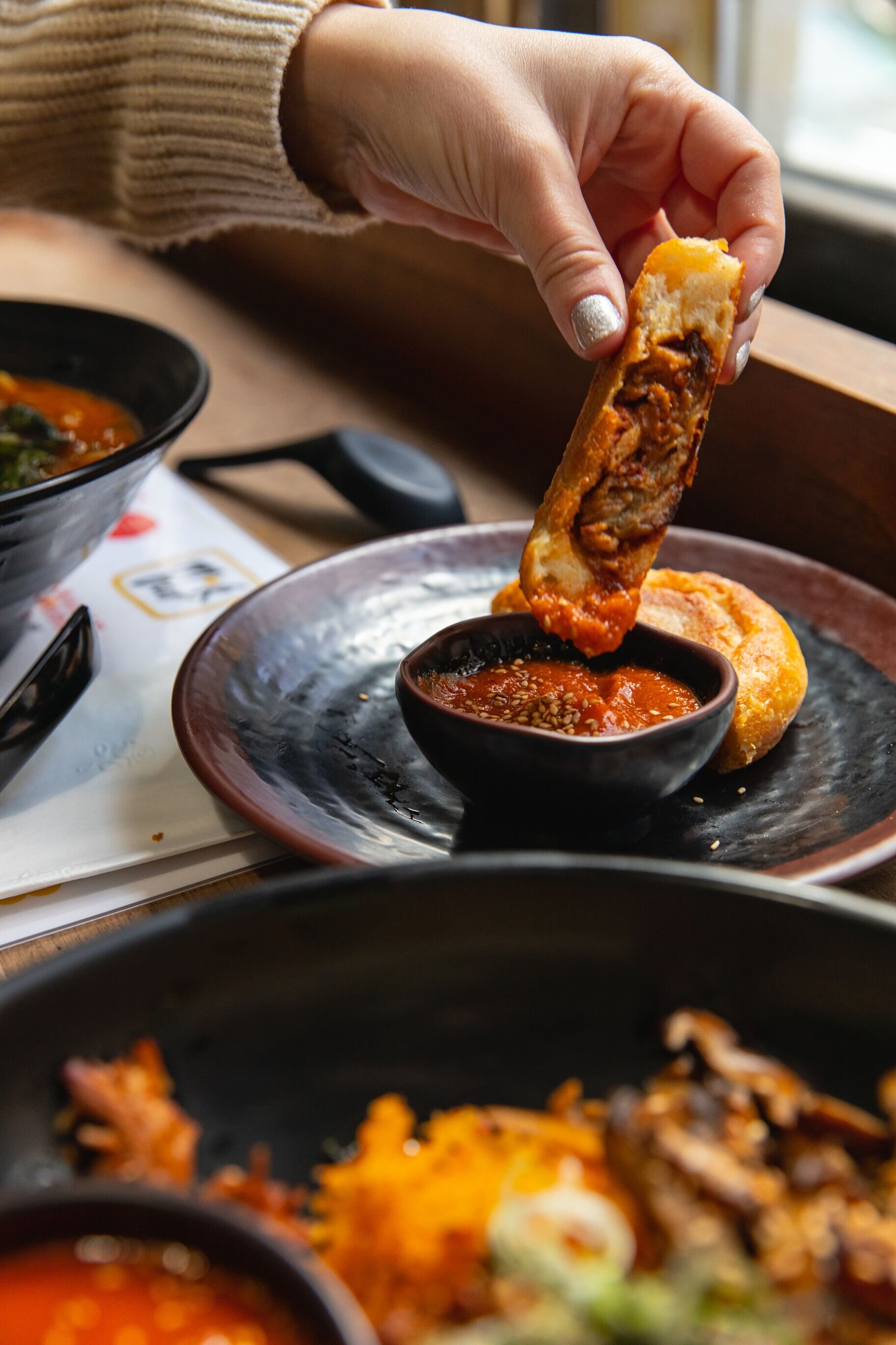 hand dipping a ho cake into red sauce 