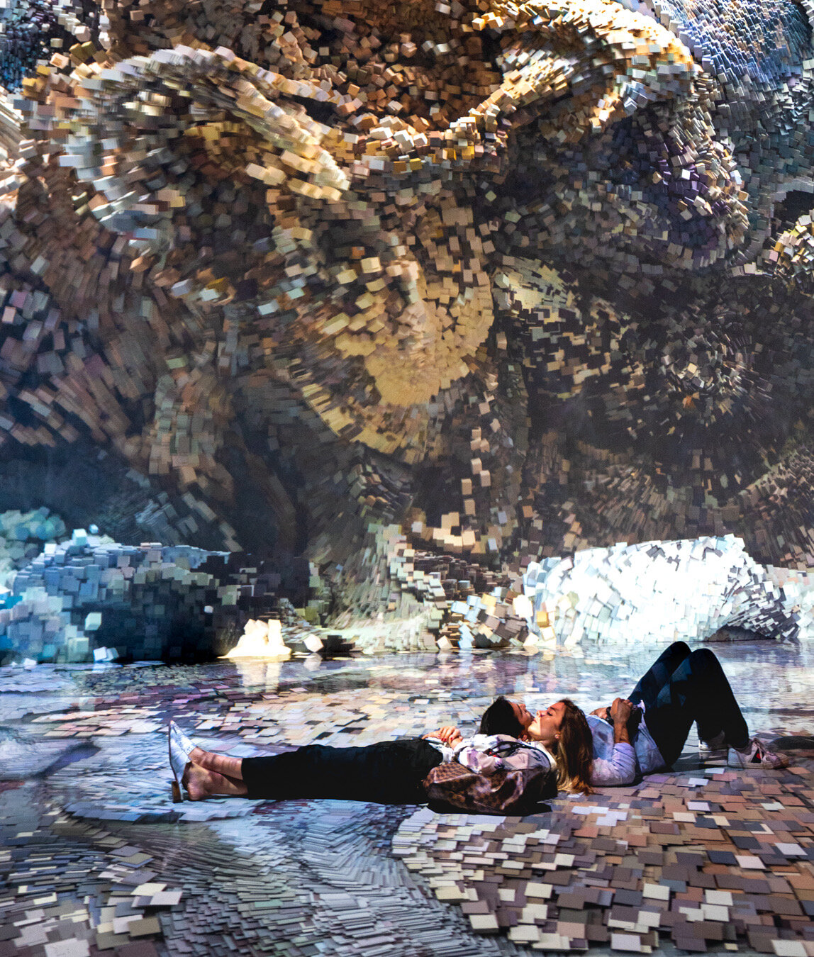 couple lying on ground with images projected on wall 