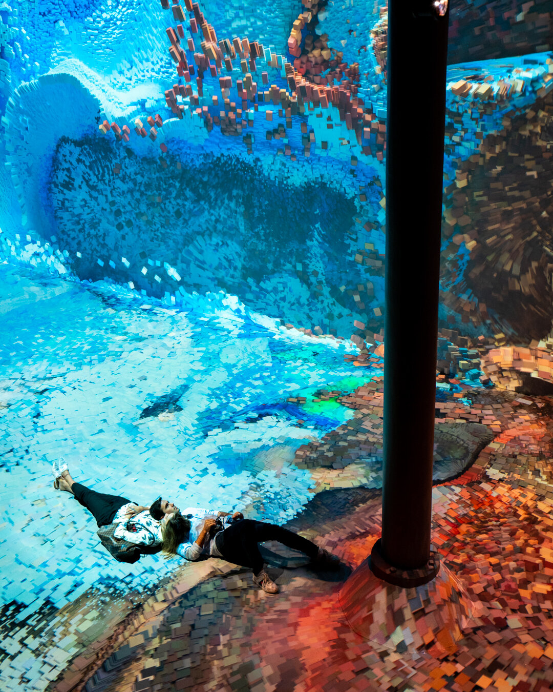 overhead shot of couple lying on ground with projections around them 